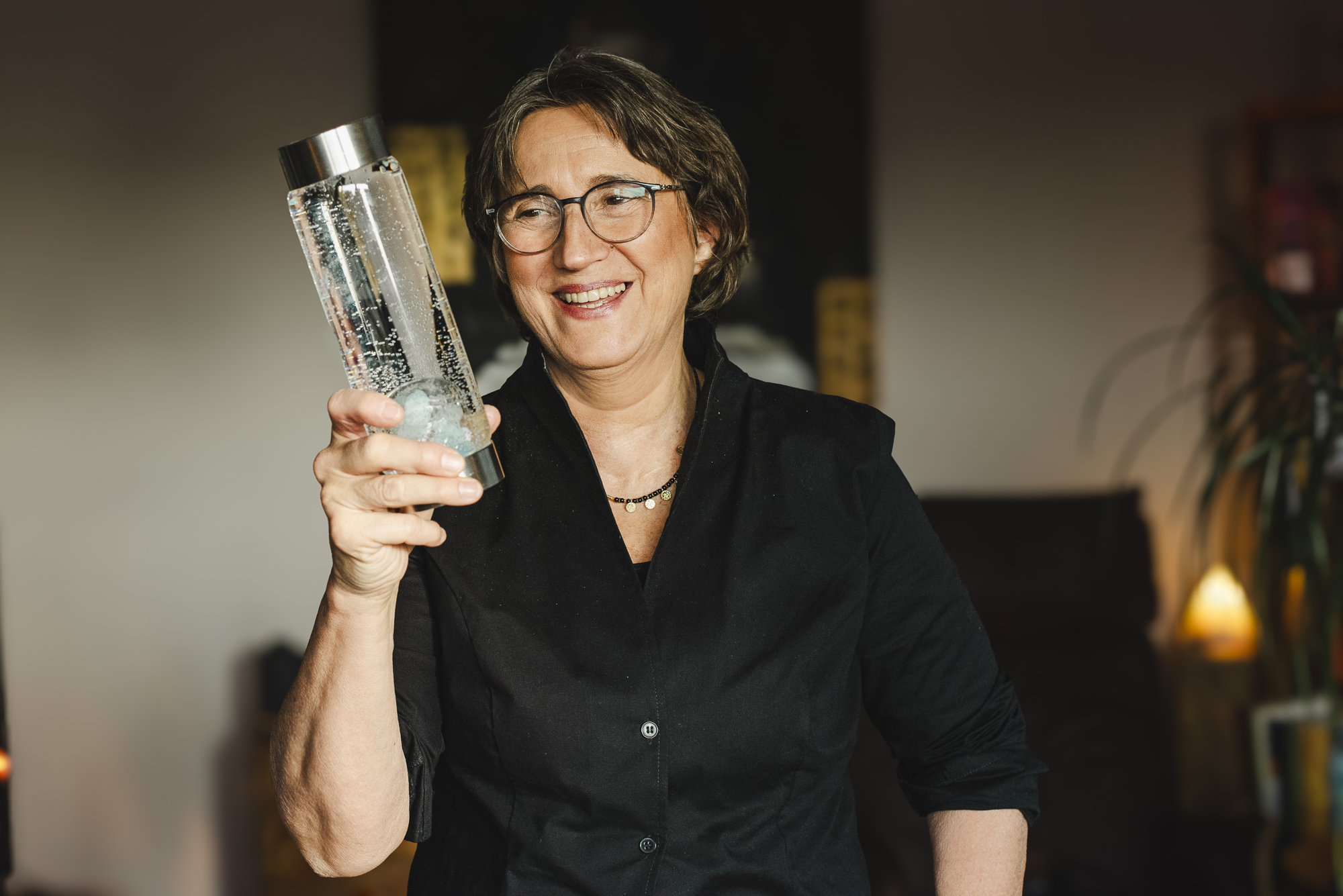Anja Freese hält eine Glasflasche mit Sprudelwasser in die Kamera